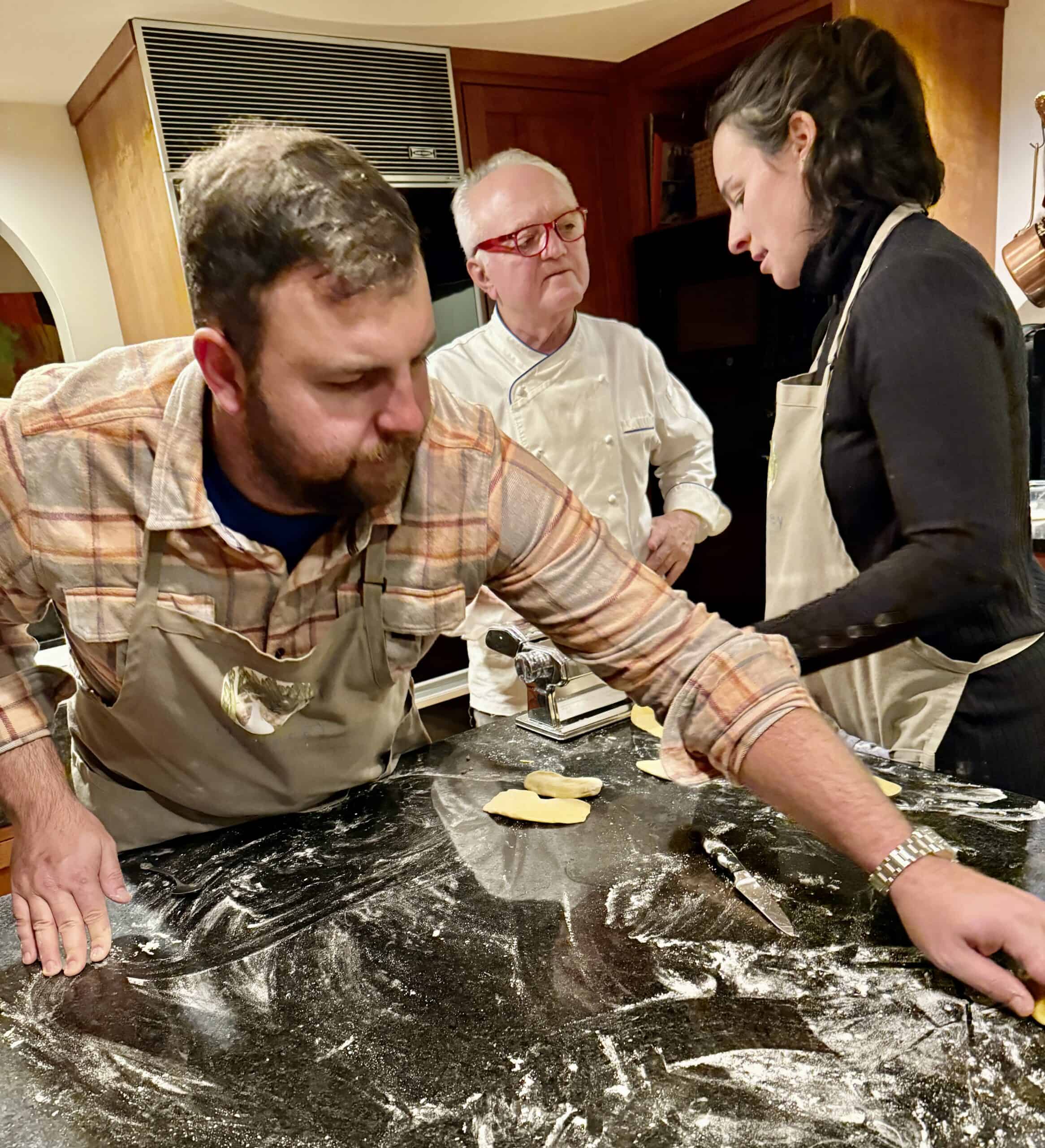 Bakers decorating a wedding cake in a cozy kitchen setting.