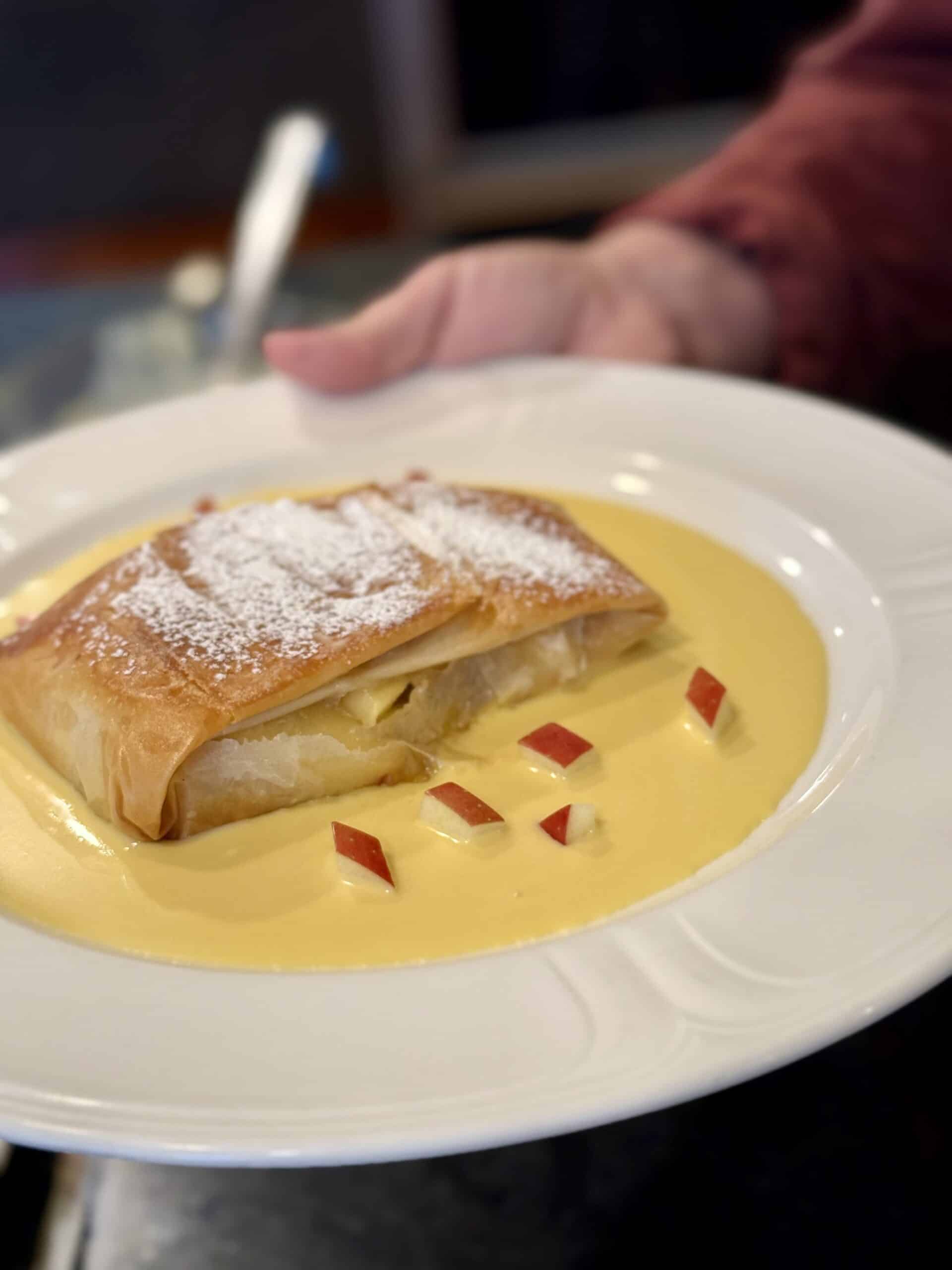 Delicious pastry dessert with custard and powdered sugar, presented on a white plate.