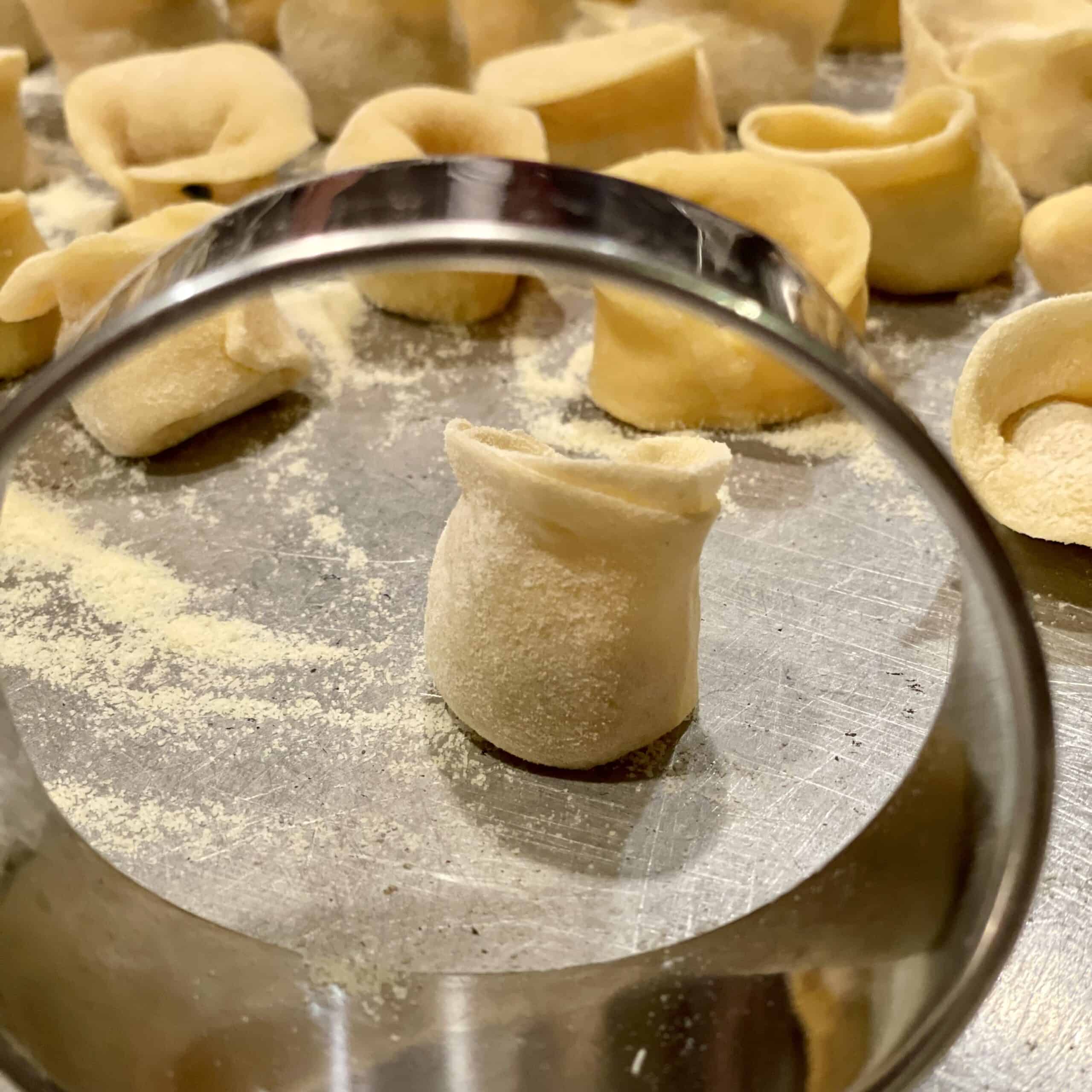 Freshly made pasta with a pasta cutter on a floured surface.