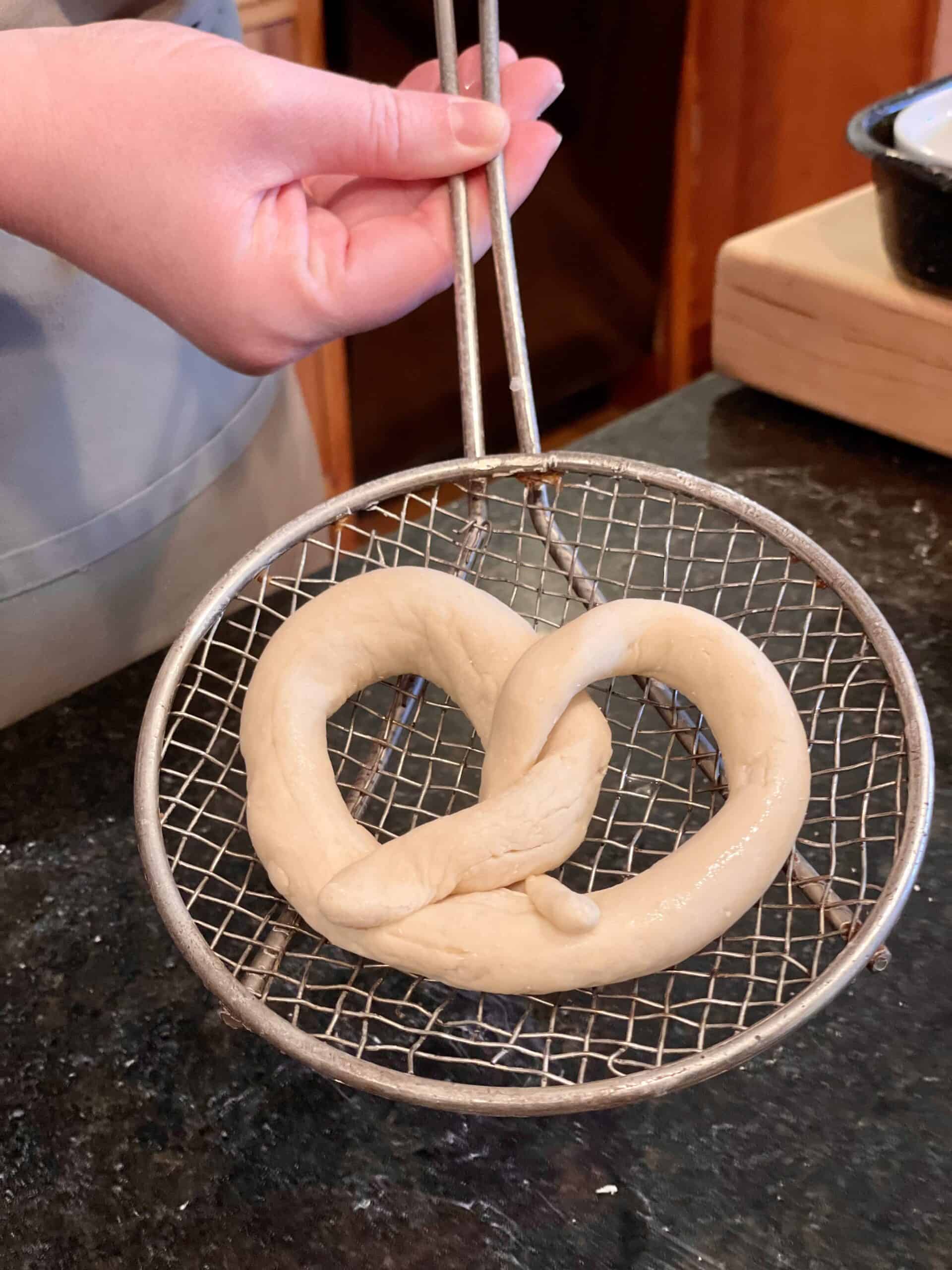 Freshly baked pretzel held with tongs at Odyssey Events.
