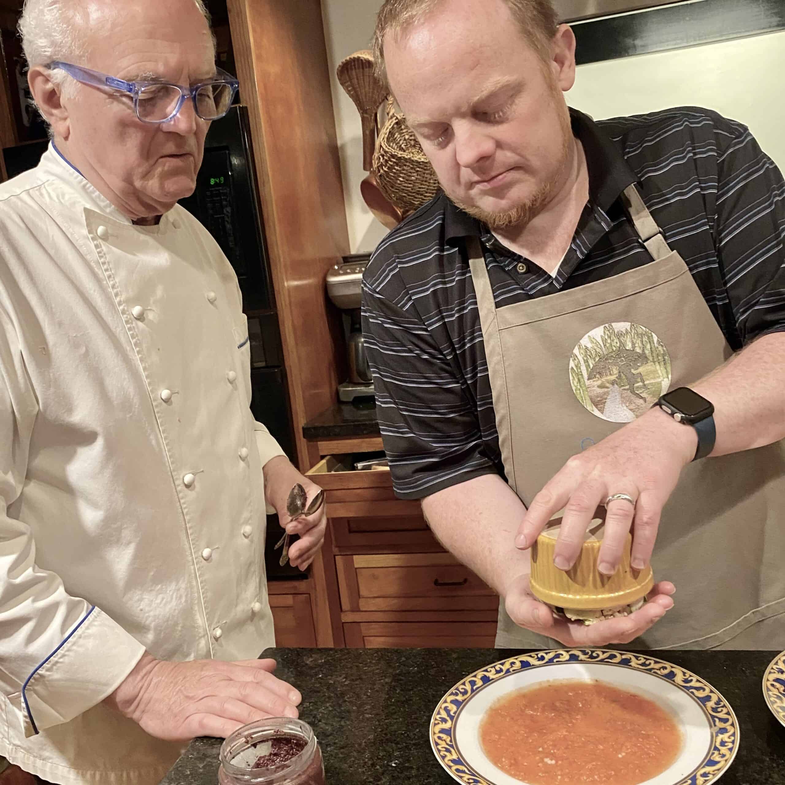 Chef and assistant cooking together in a commercial kitchen setting.