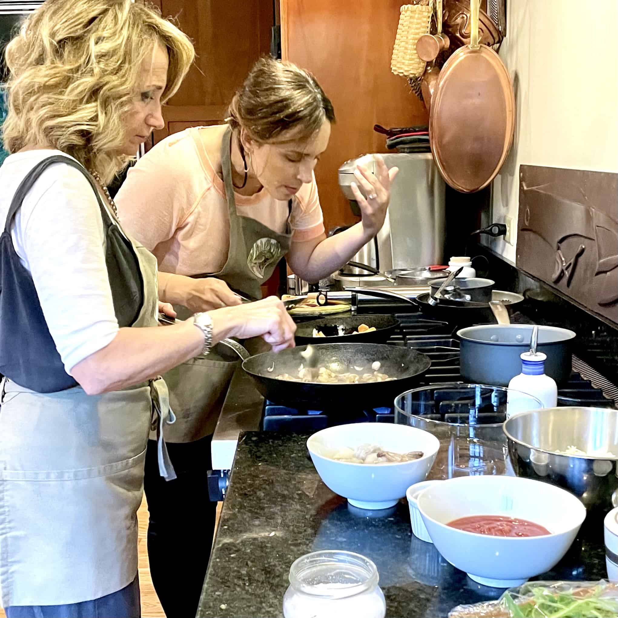 Cooking class with two women preparing food in a cozy kitchen.