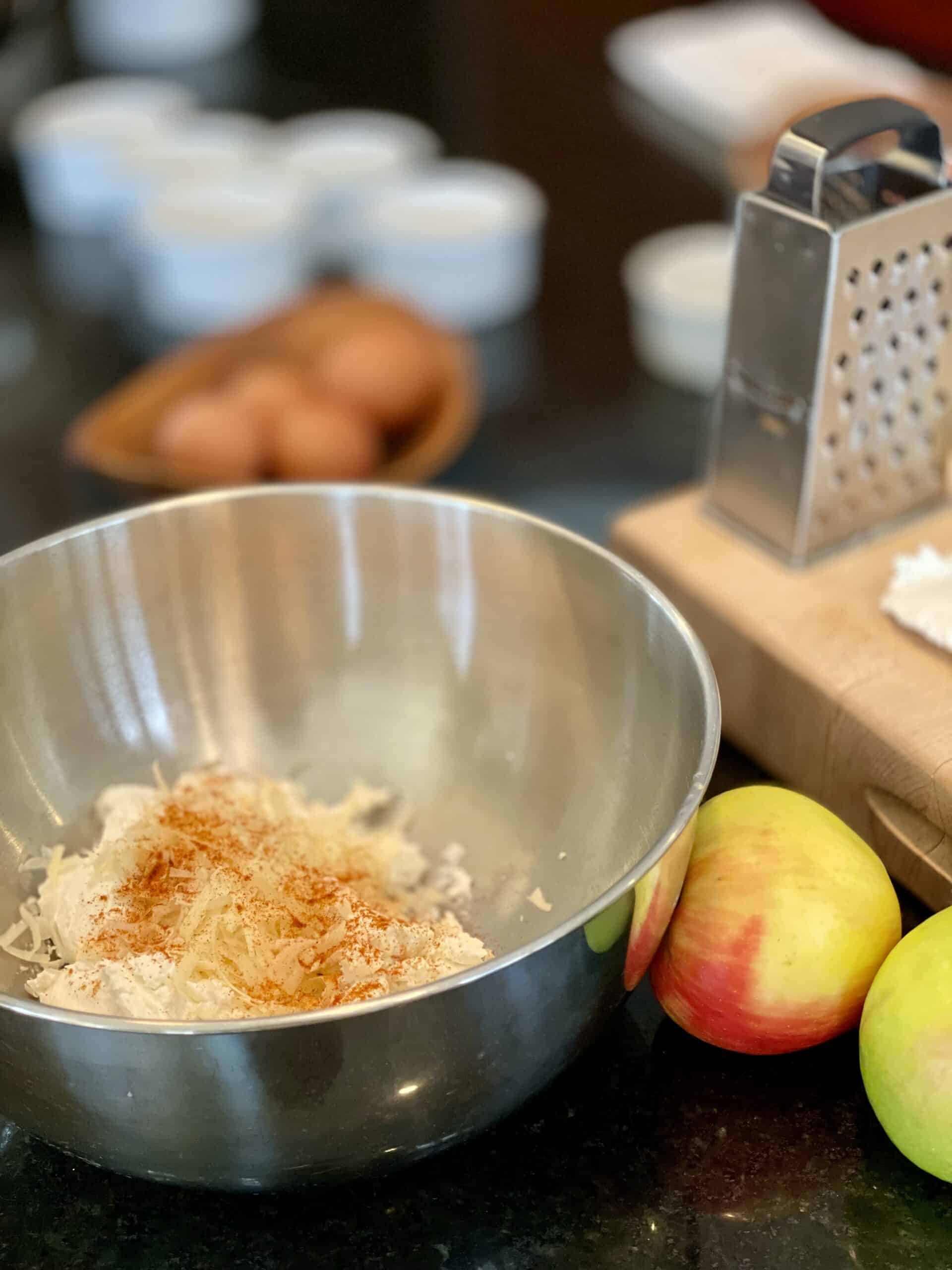 Baking ingredients including apples, eggs, and flour on a kitchen countertop.