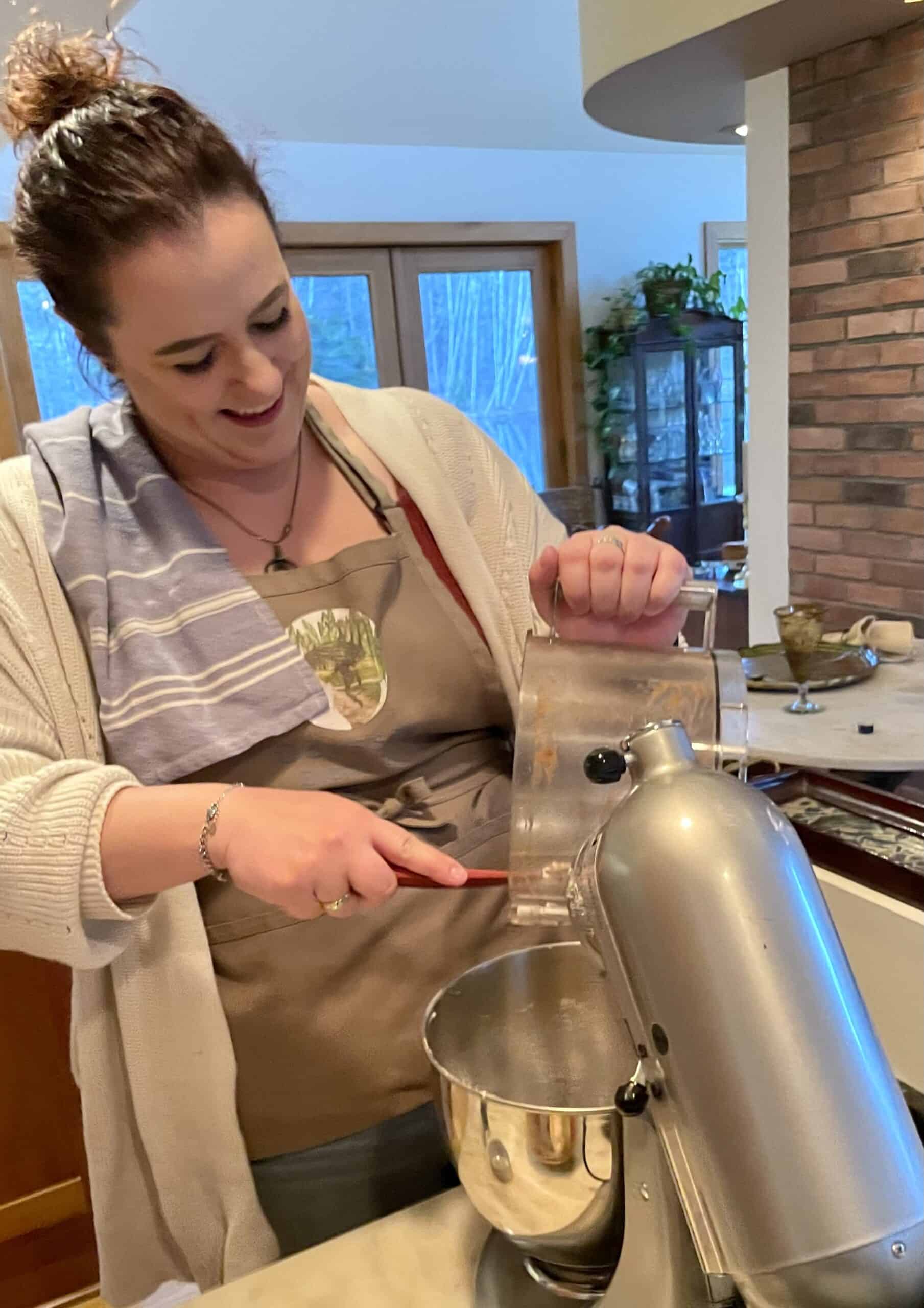 Woman baking with stand mixer in cozy kitchen setting.