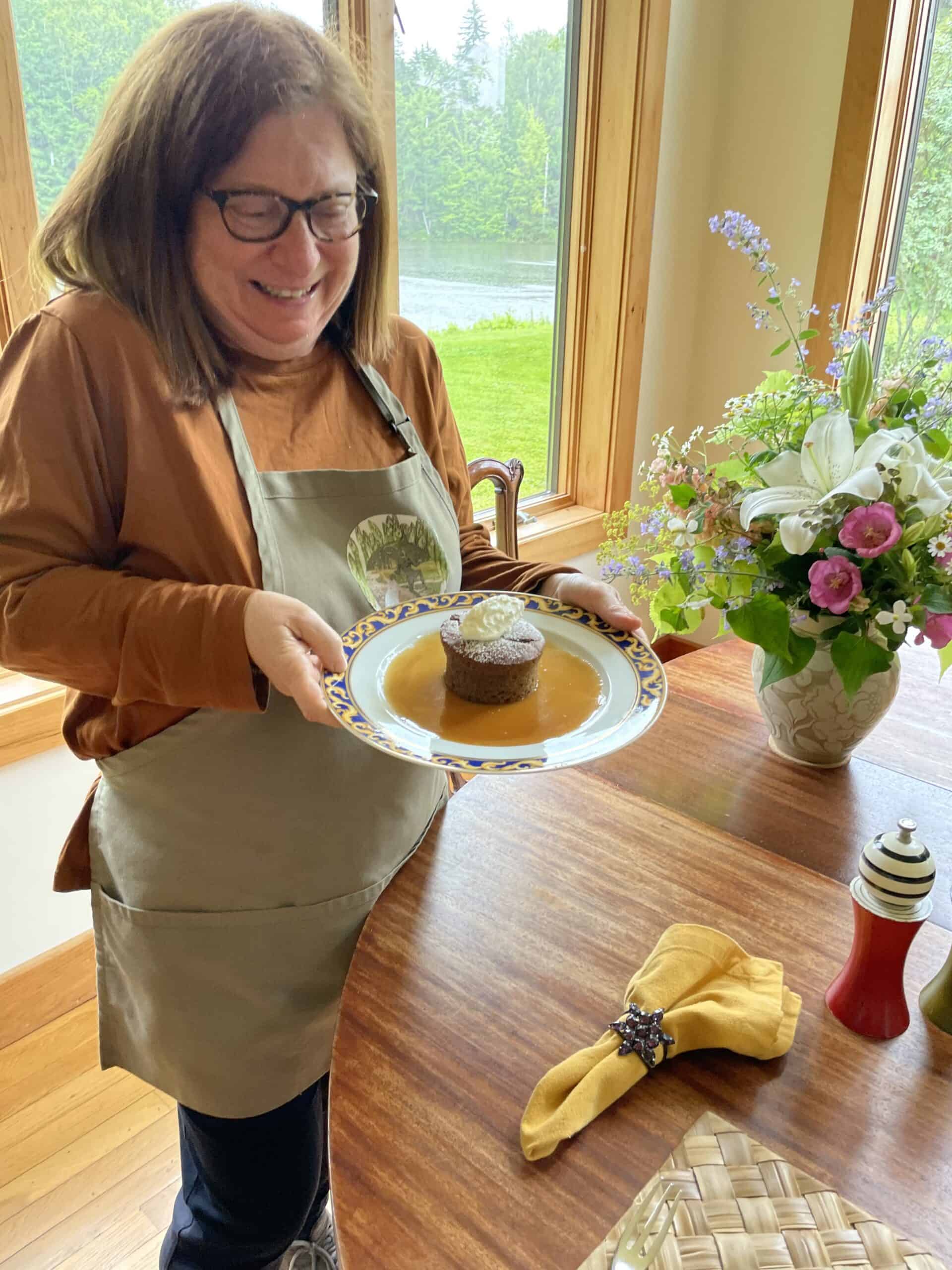 Happy woman holding a cake on a decorative plate, celebrating a special occasion at Odyssey Events.