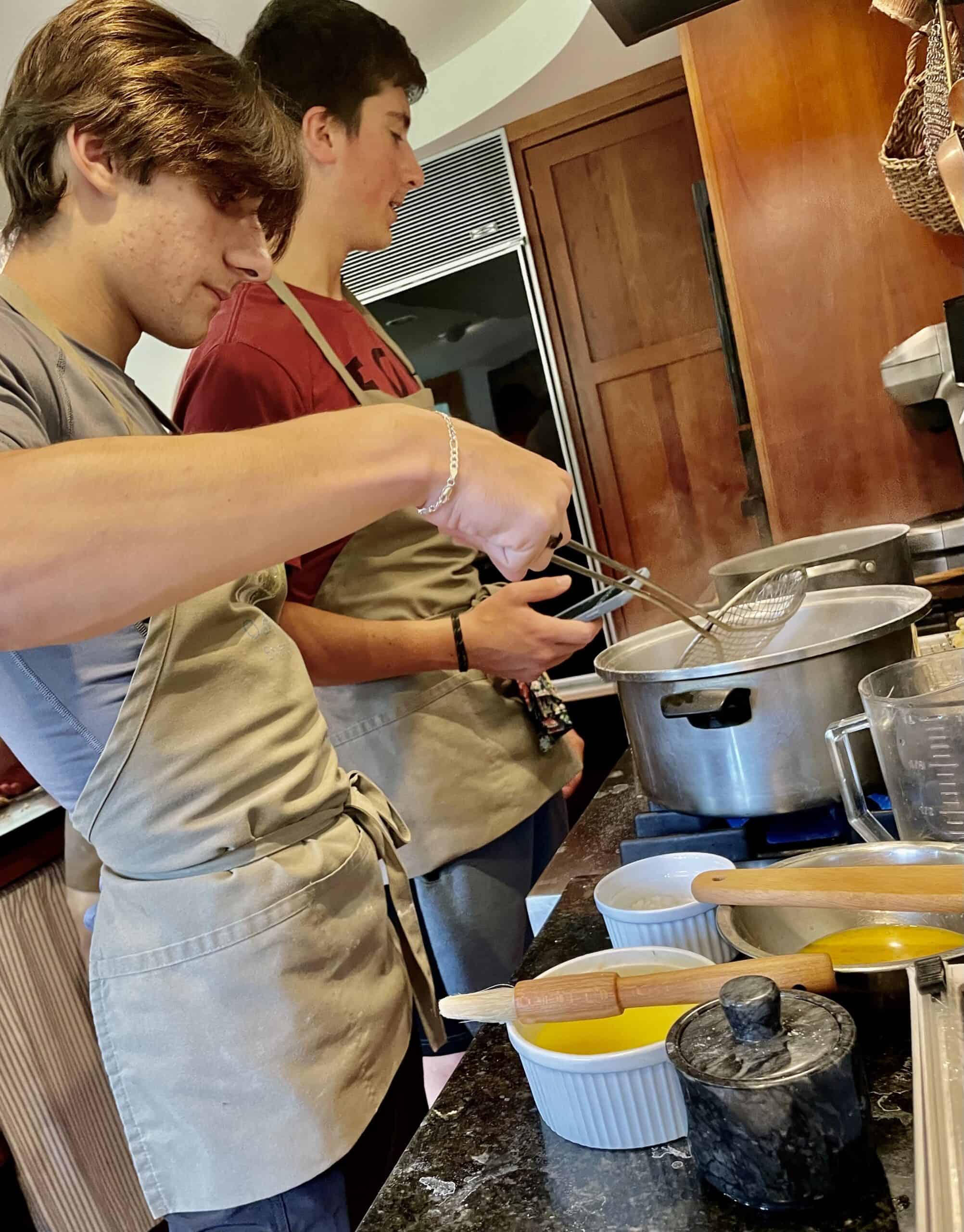 Cooking class with young participants preparing food in a professional kitchen.