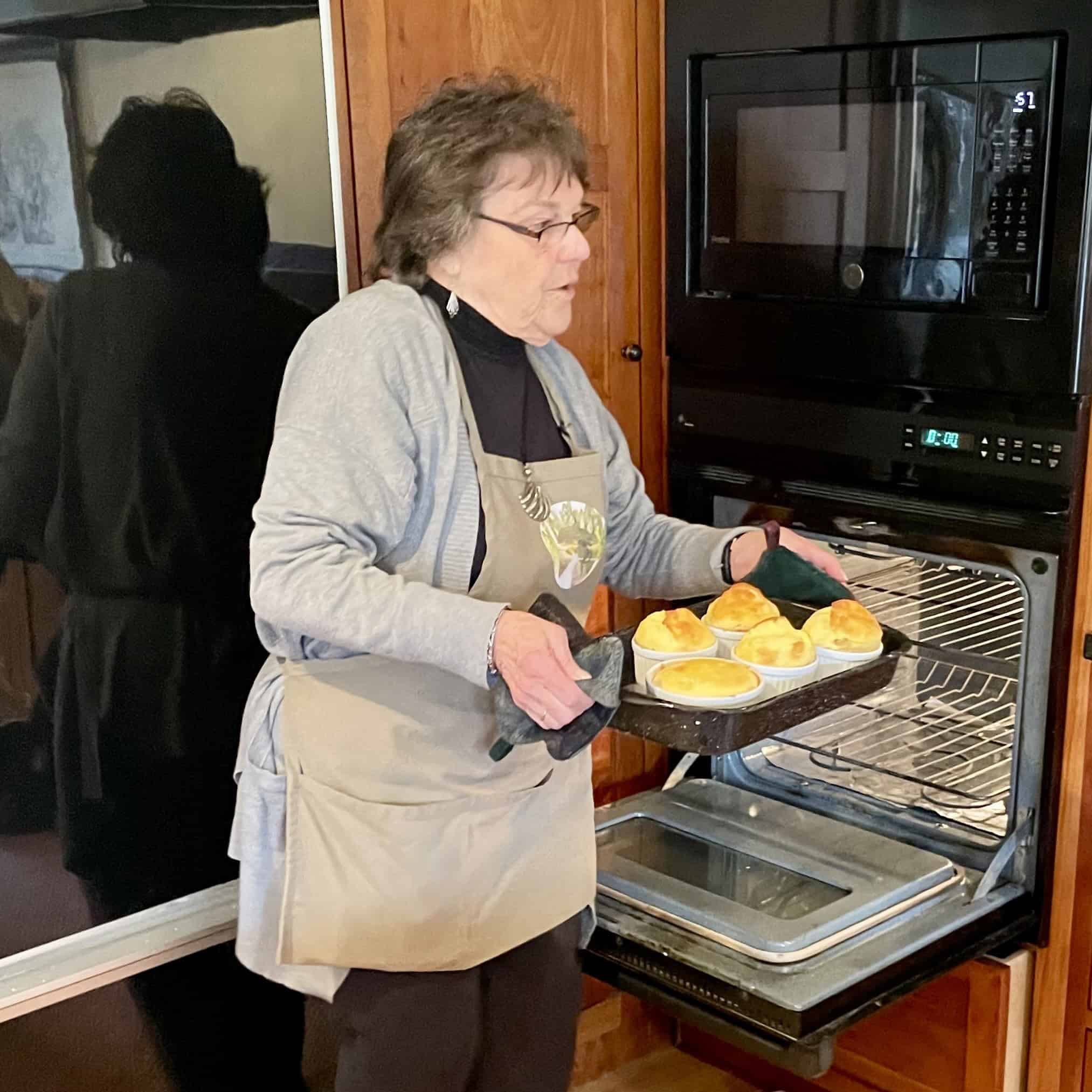Woman placing bread rolls in oven for baking.