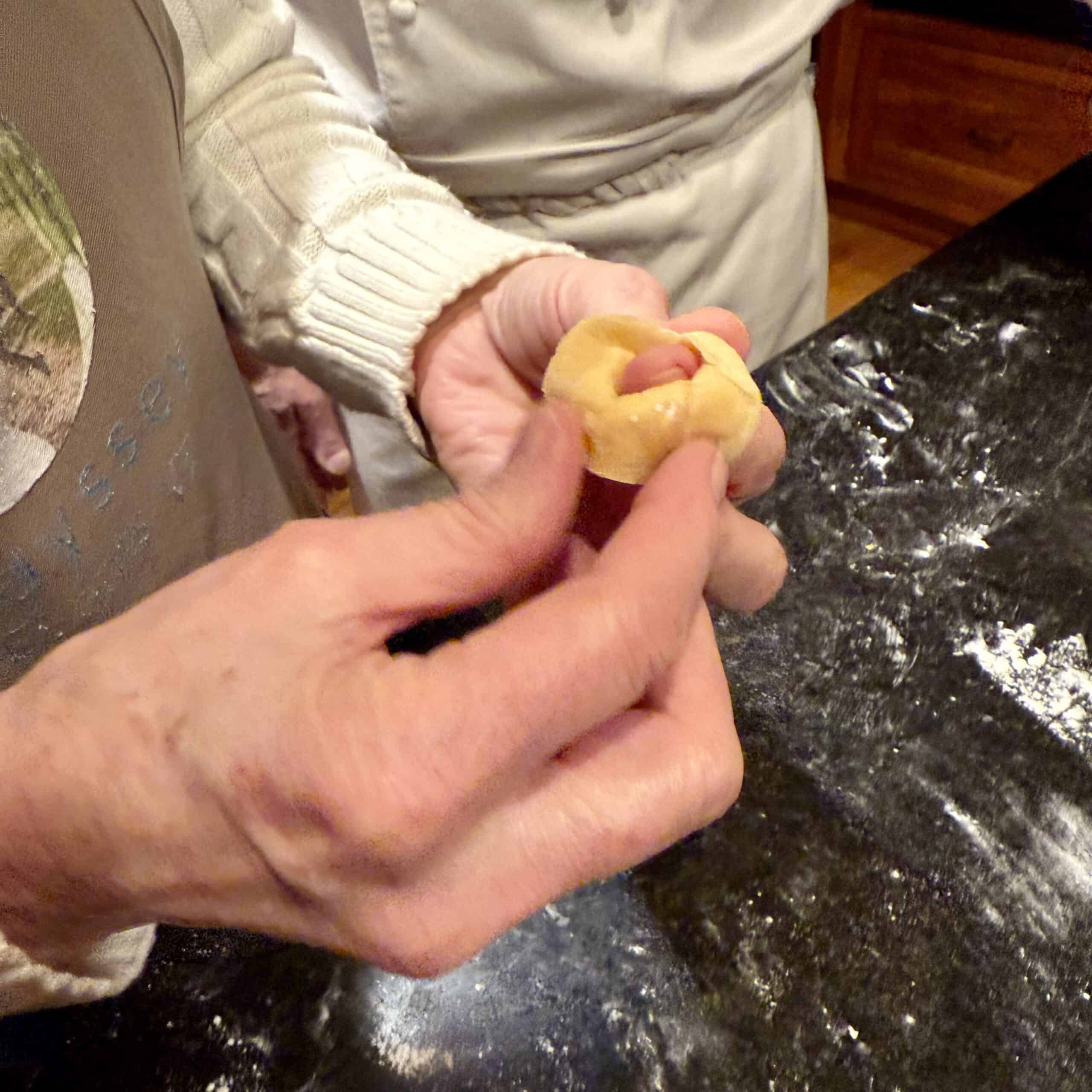 Hands shaping dough for baking in a kitchen setting.