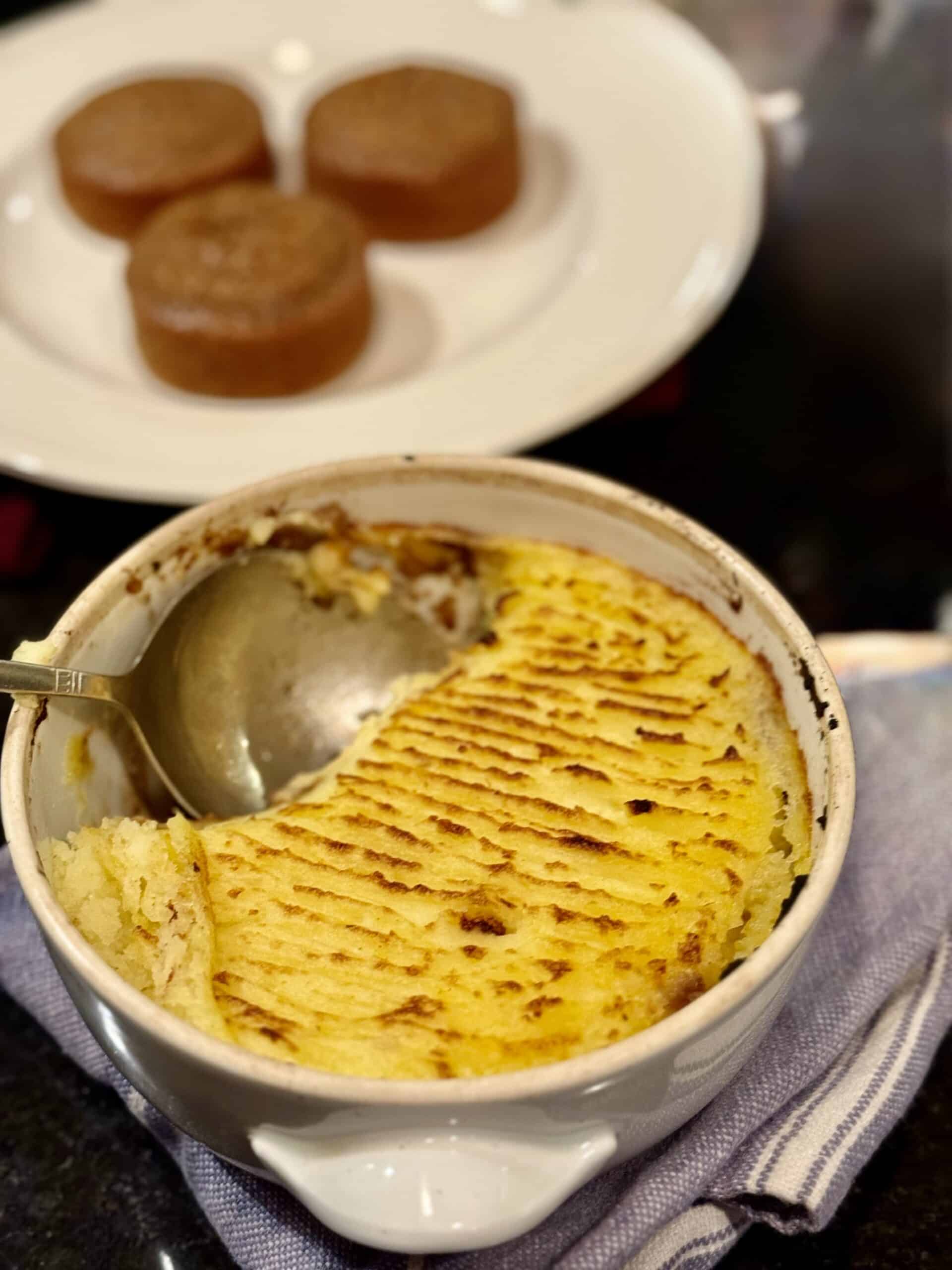 Classic shepherd's pie with mashed potatoes and meat patties on a white plate.