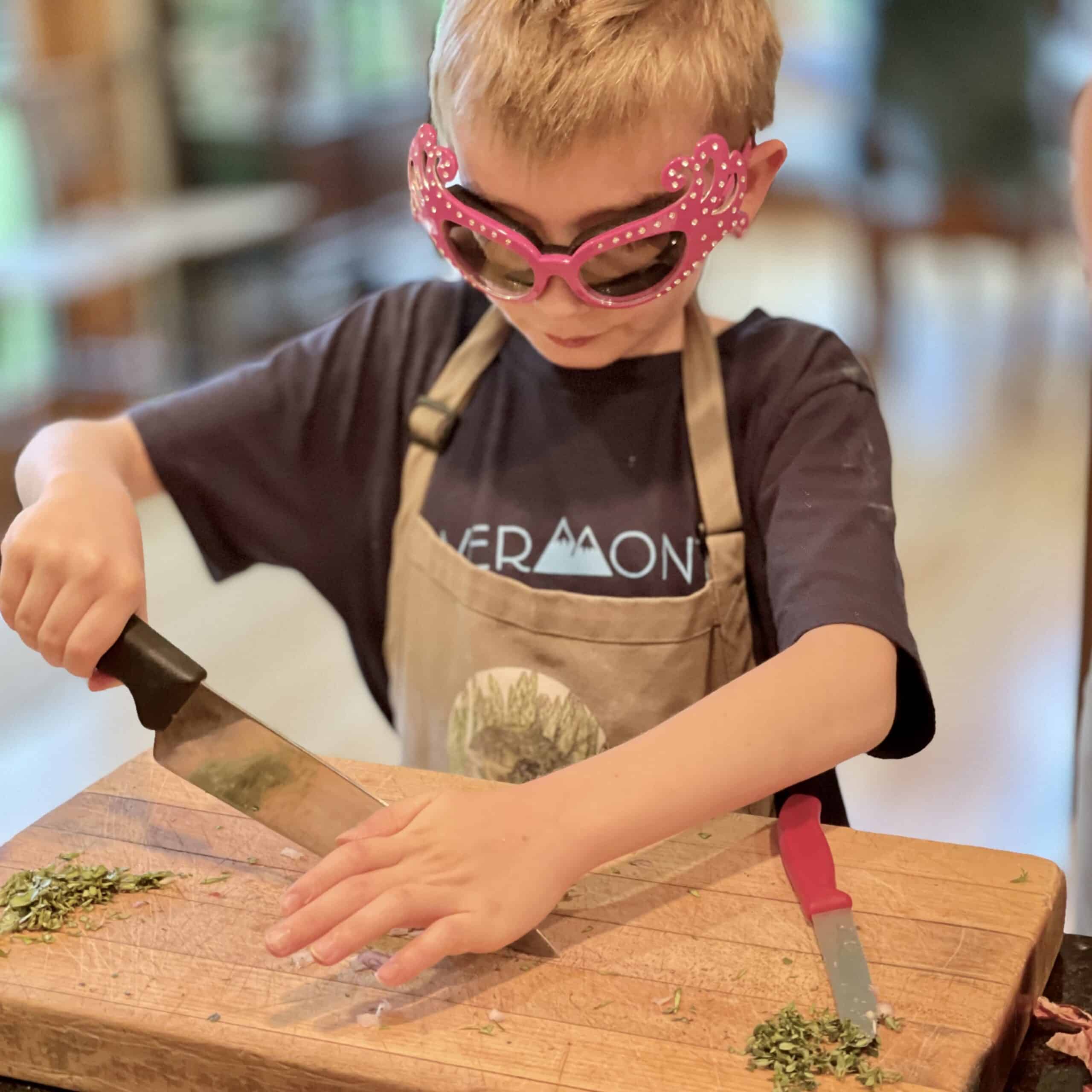 Child cooking with a knife and herbs, enjoying a fun activity at Odyssey Events.