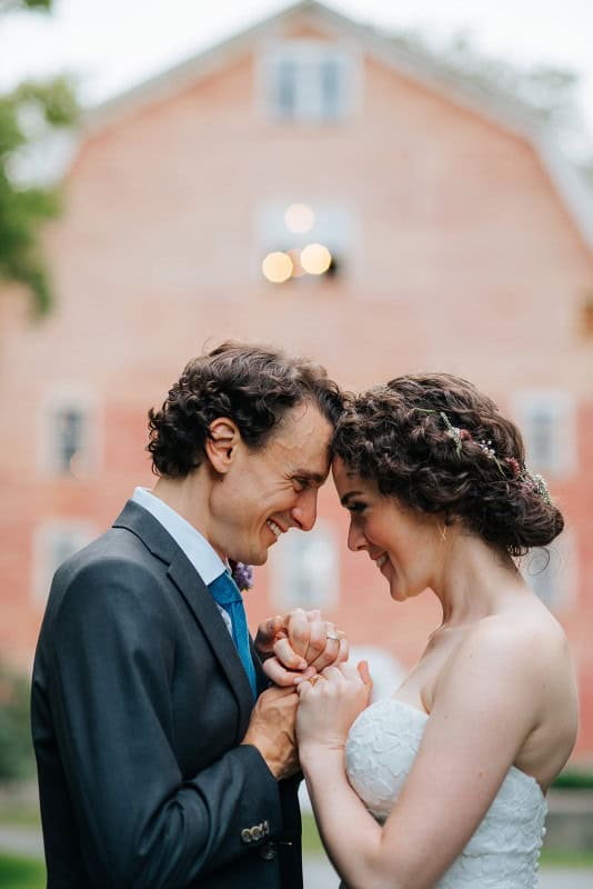 Romantic wedding couple holding hands and smiling at each other outdoors, celebrating love and commi.
