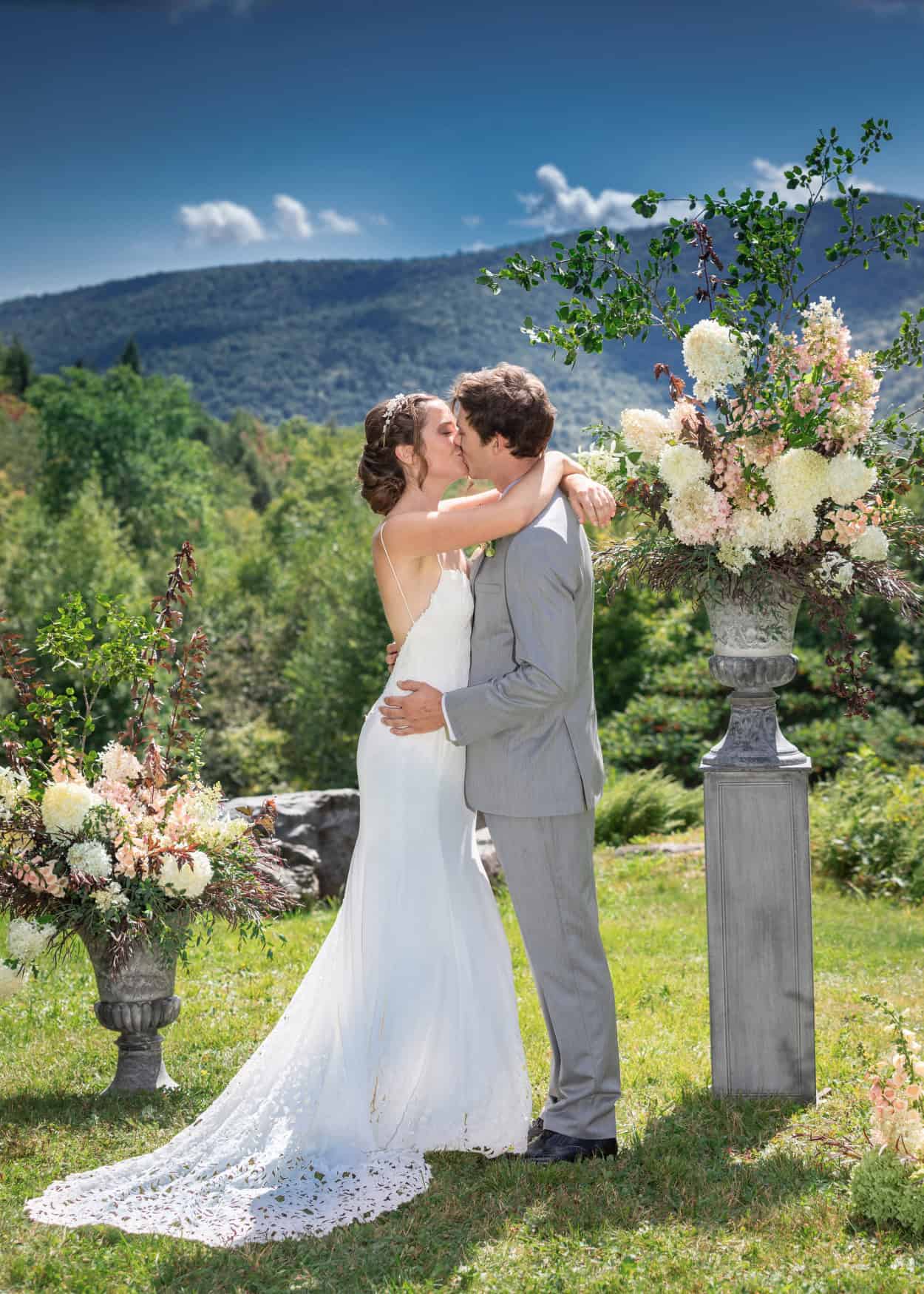 Wedding couple sharing a kiss in a scenic garden setting.