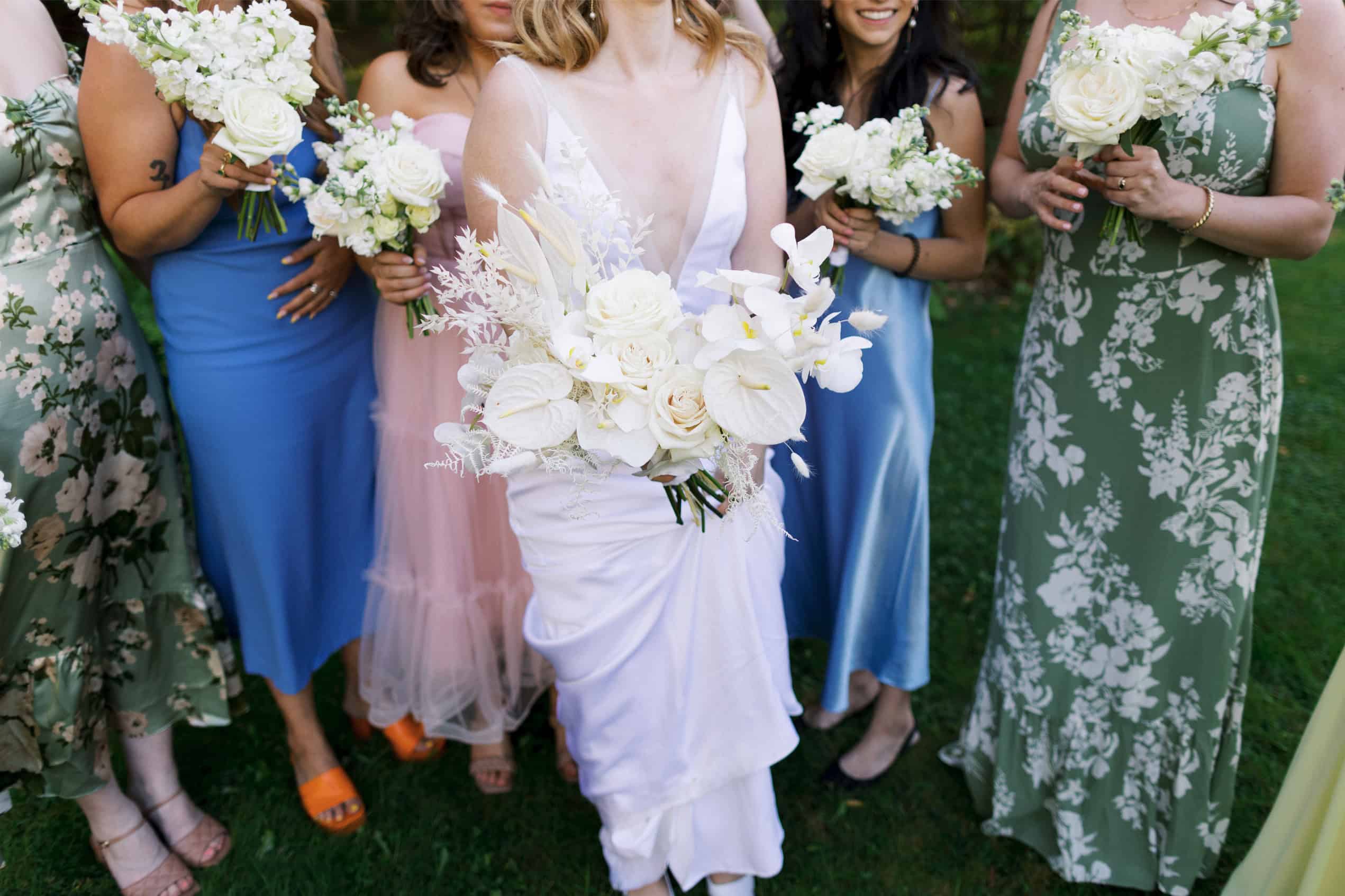 Bridesmaids holding white floral bouquets at an outdoor wedding ceremony.