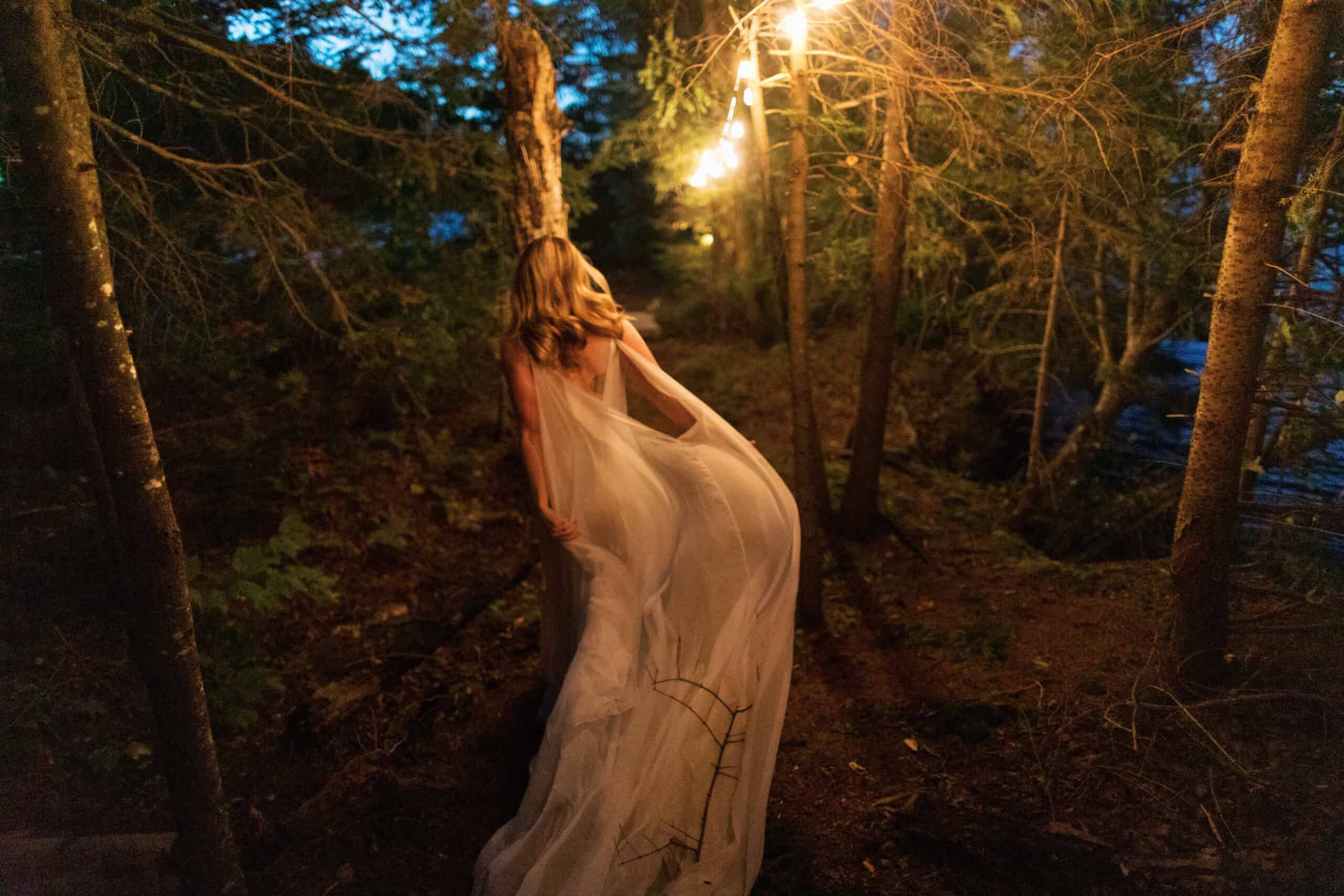 Elegant outdoor evening event with string lights in a forest setting.
