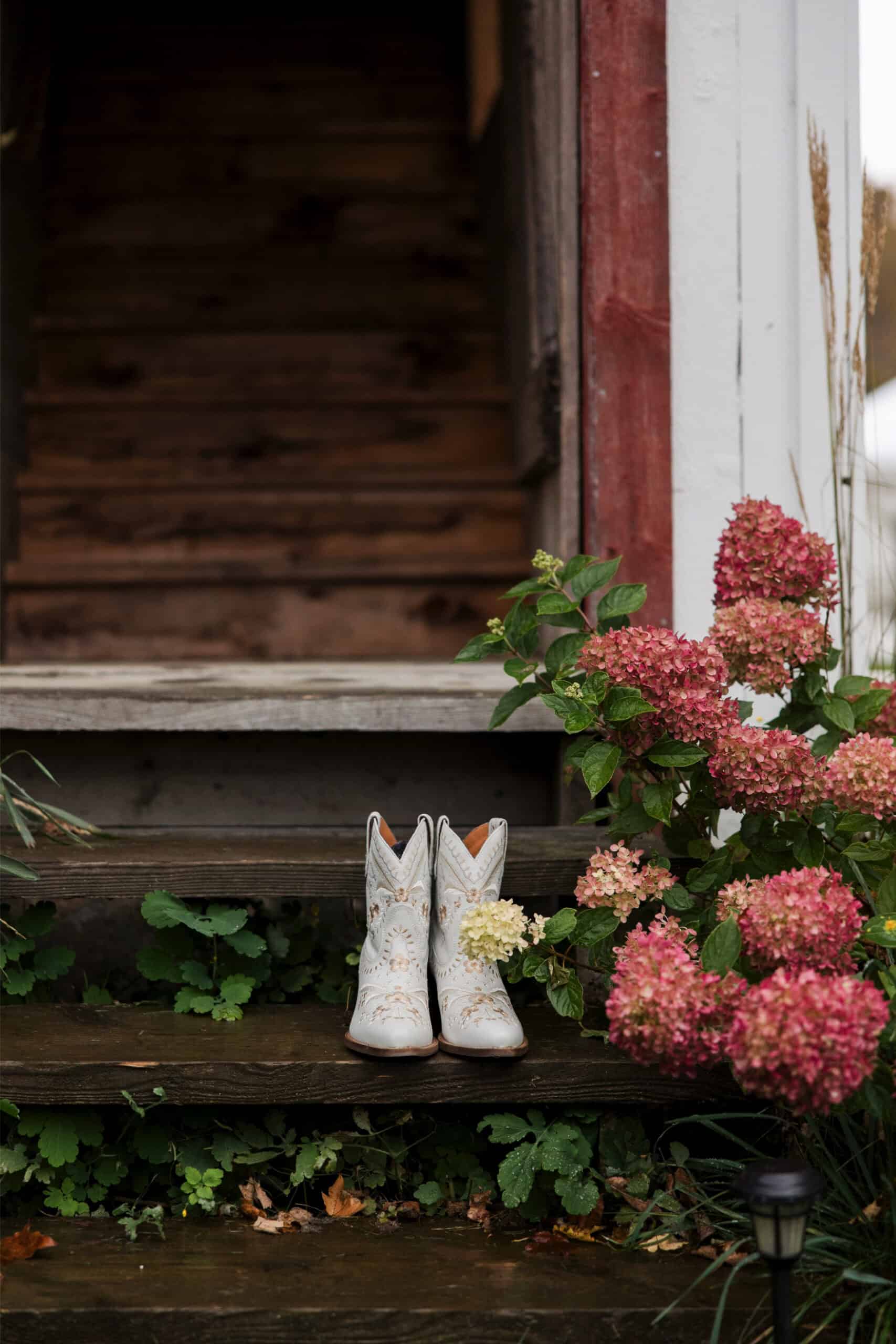 Cowboy boots with floral accents on rustic wooden steps.