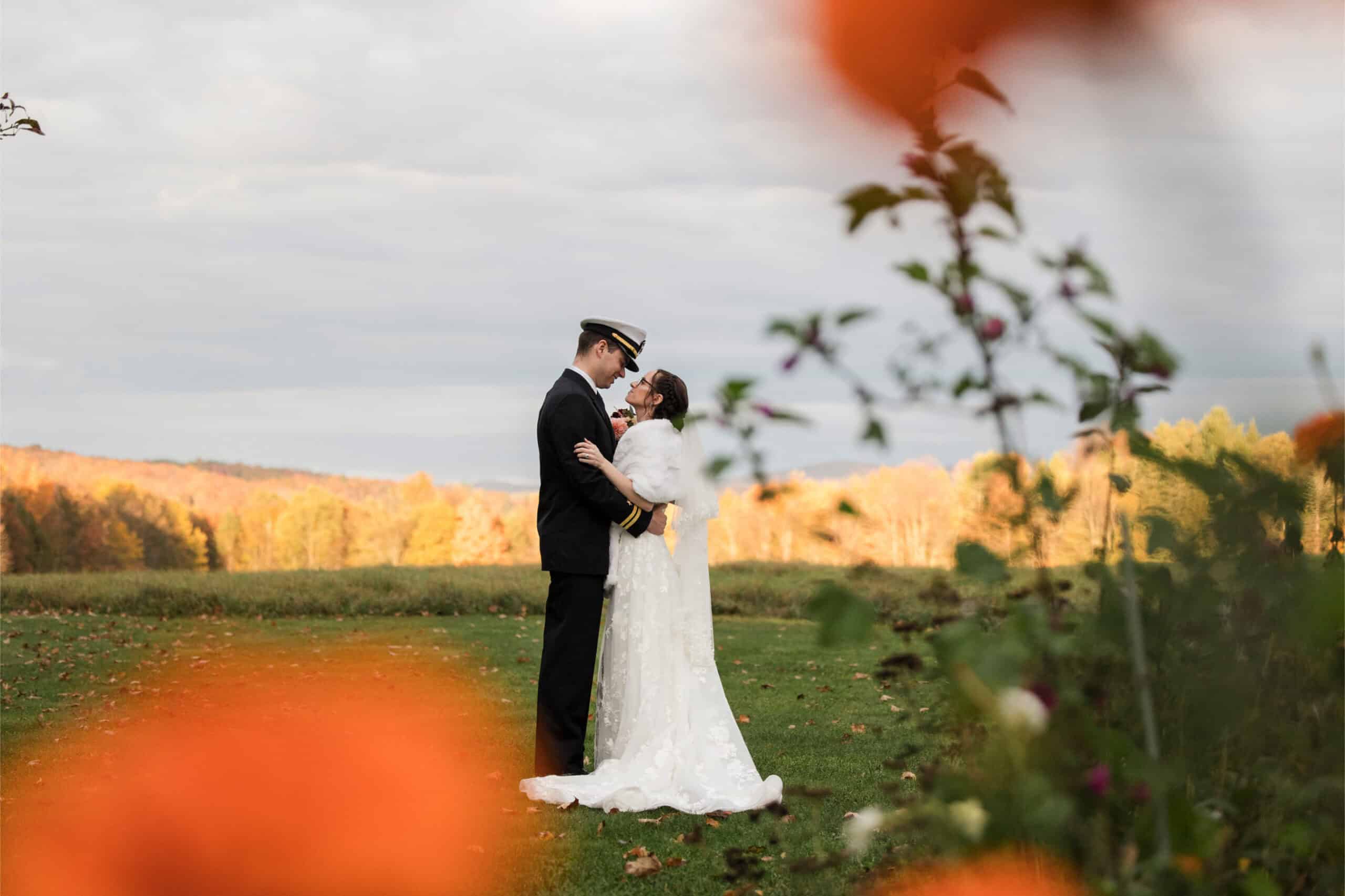 Wedding couple in uniform embracing in scenic outdoor setting.