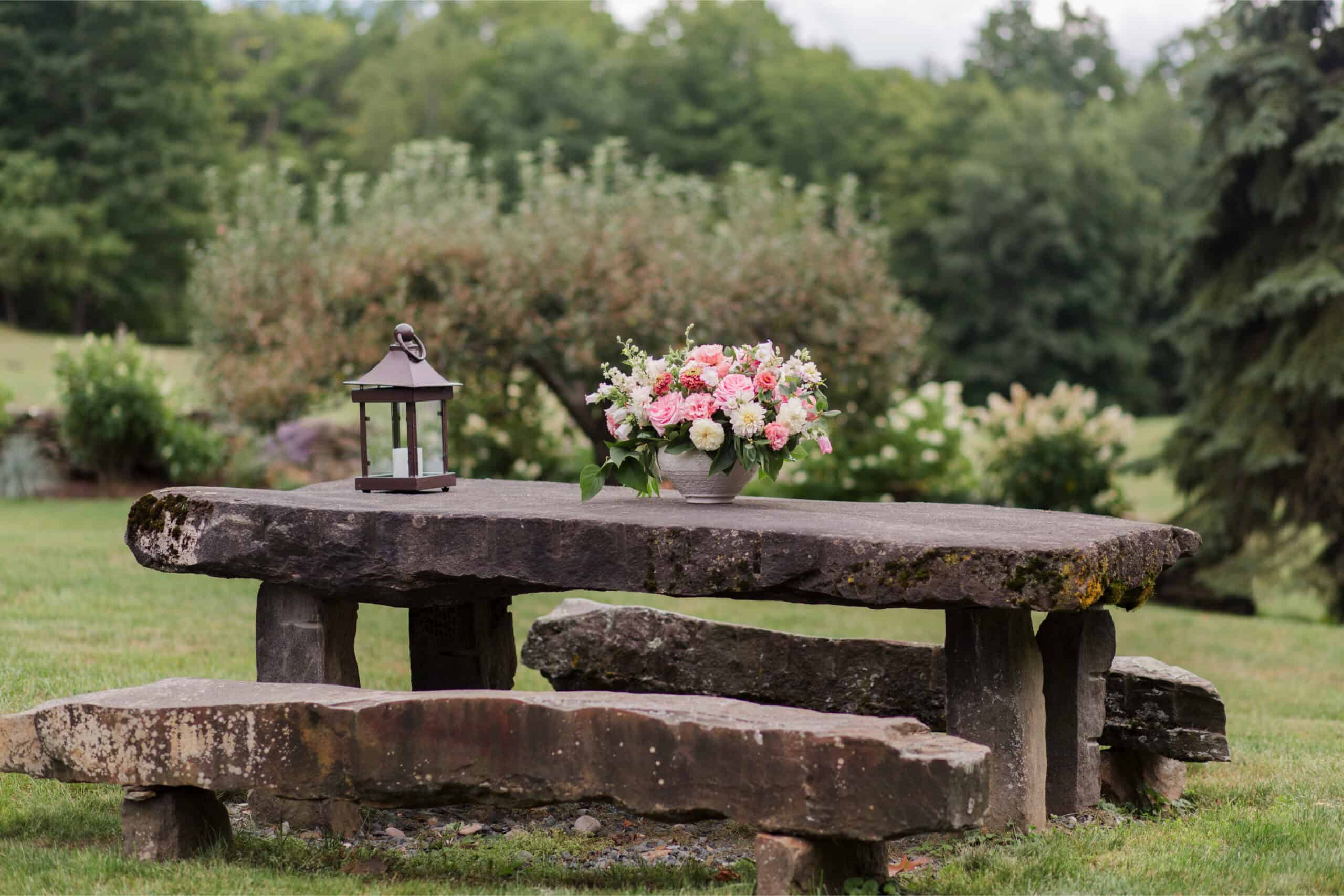 Outdoor garden table with flowers and lantern for event decor.