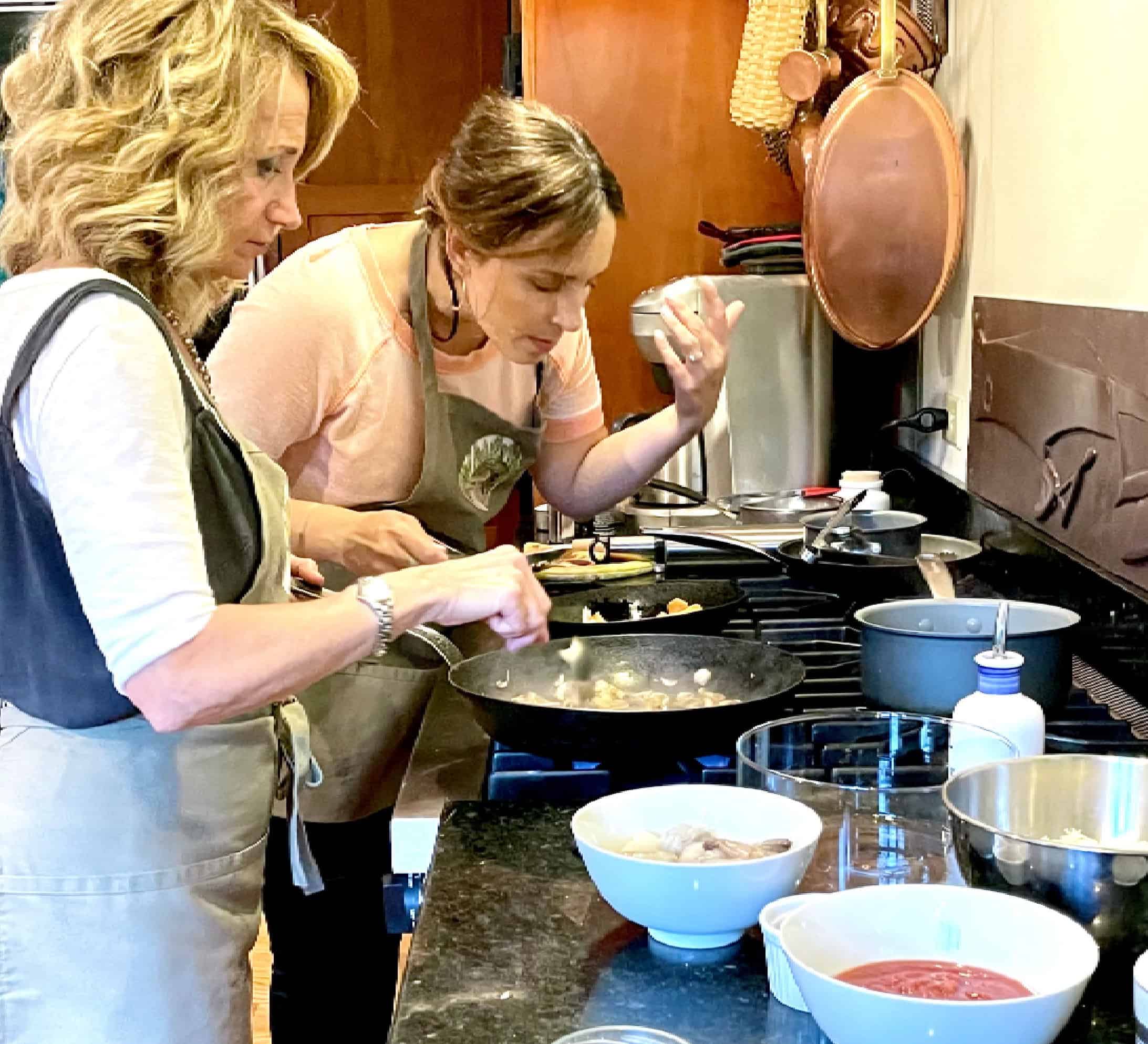 Cooking class with two women preparing meals in a cozy kitchen setting.