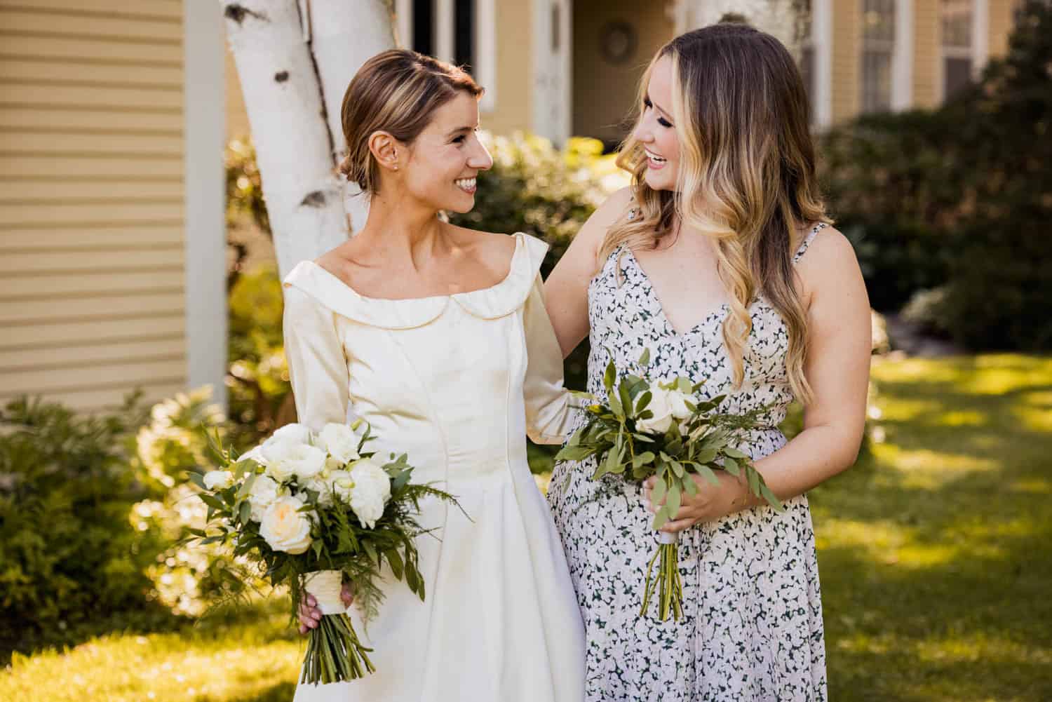 Wedding celebration with two women holding flowers outdoors.