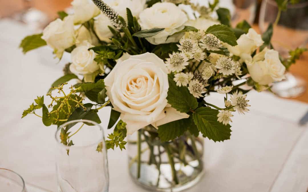 Elegant white floral centerpiece with roses and greenery for wedding decor.