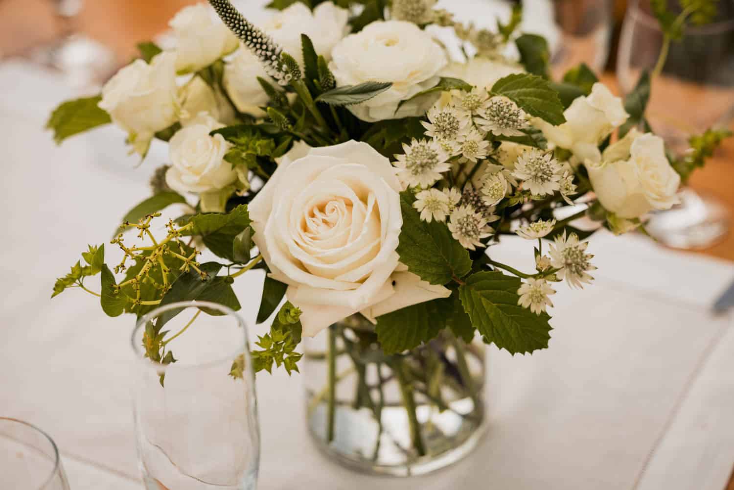 Elegant white floral centerpiece with roses and greenery for wedding decor.
