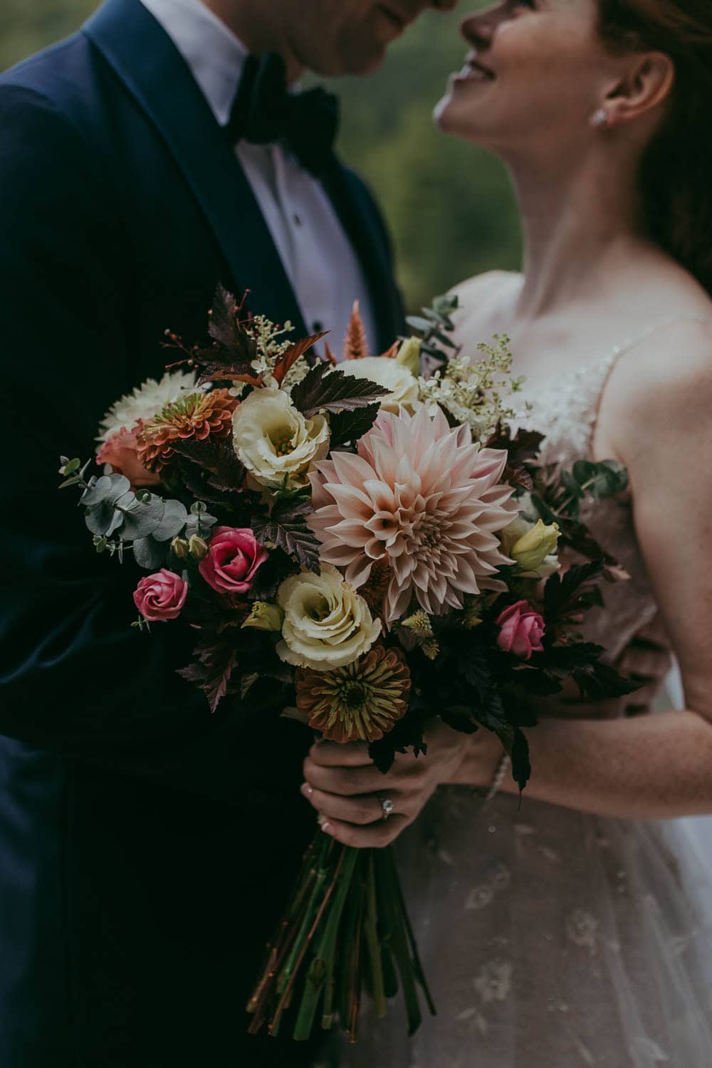 Bride and groom holding a beautiful floral bouquet at their wedding.