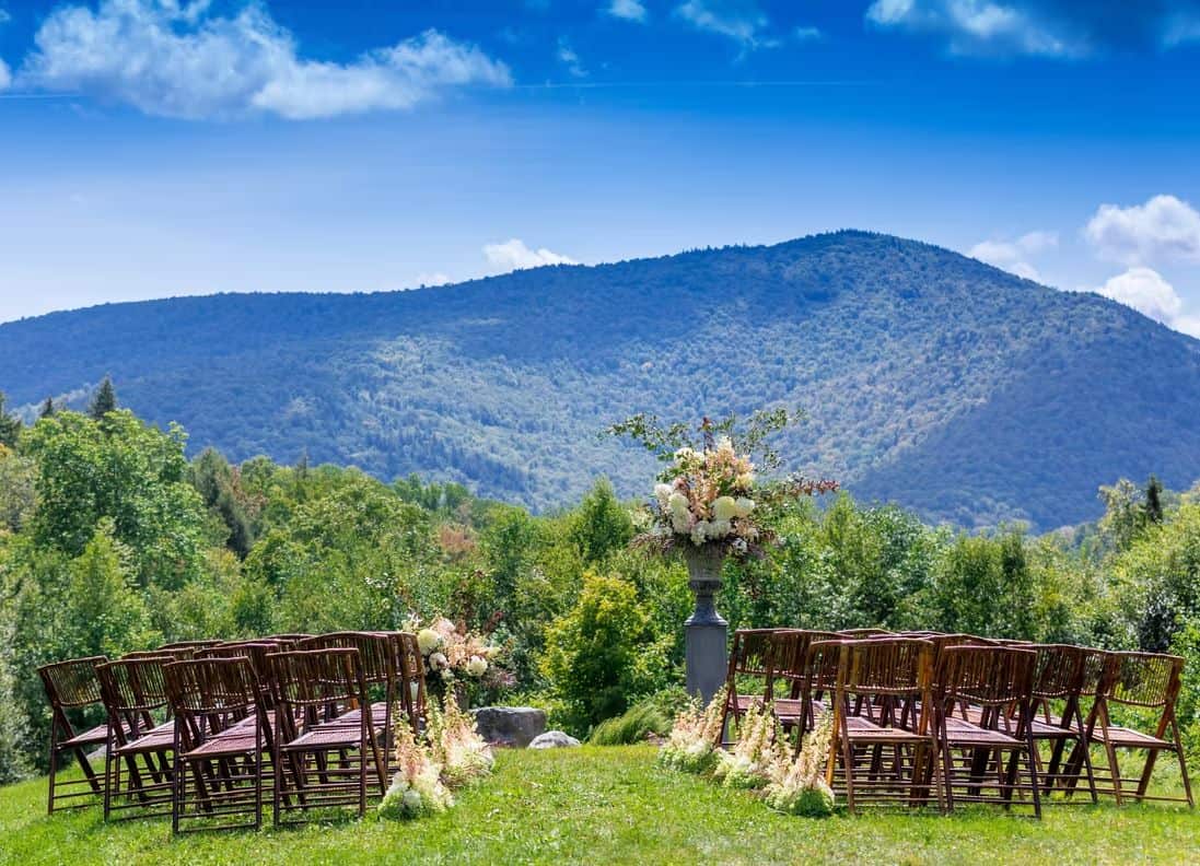 Mountain wedding ceremony setup with chairs and floral decor in a scenic outdoor location.