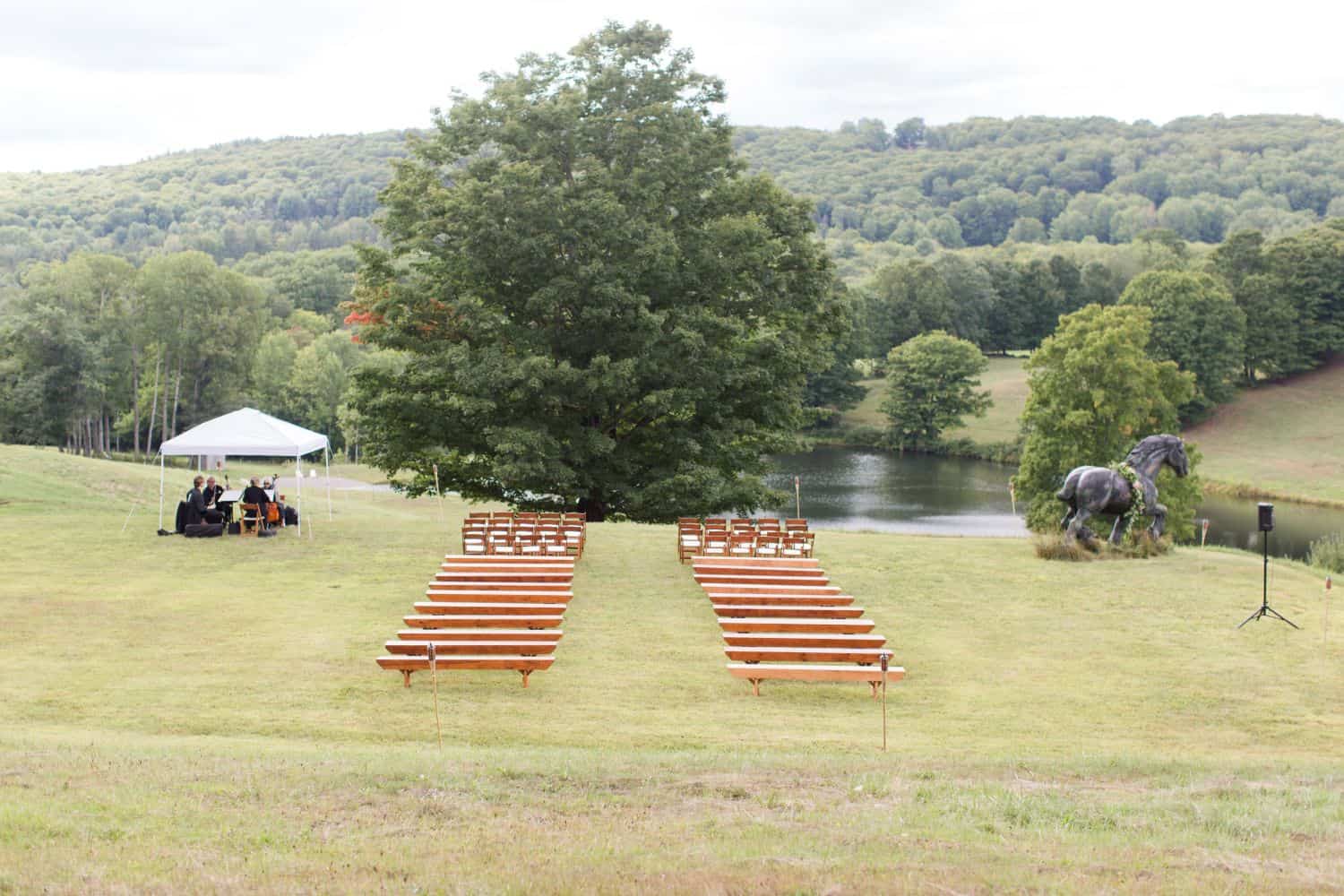 Outdoor wedding ceremony setup with benches and scenic landscape.