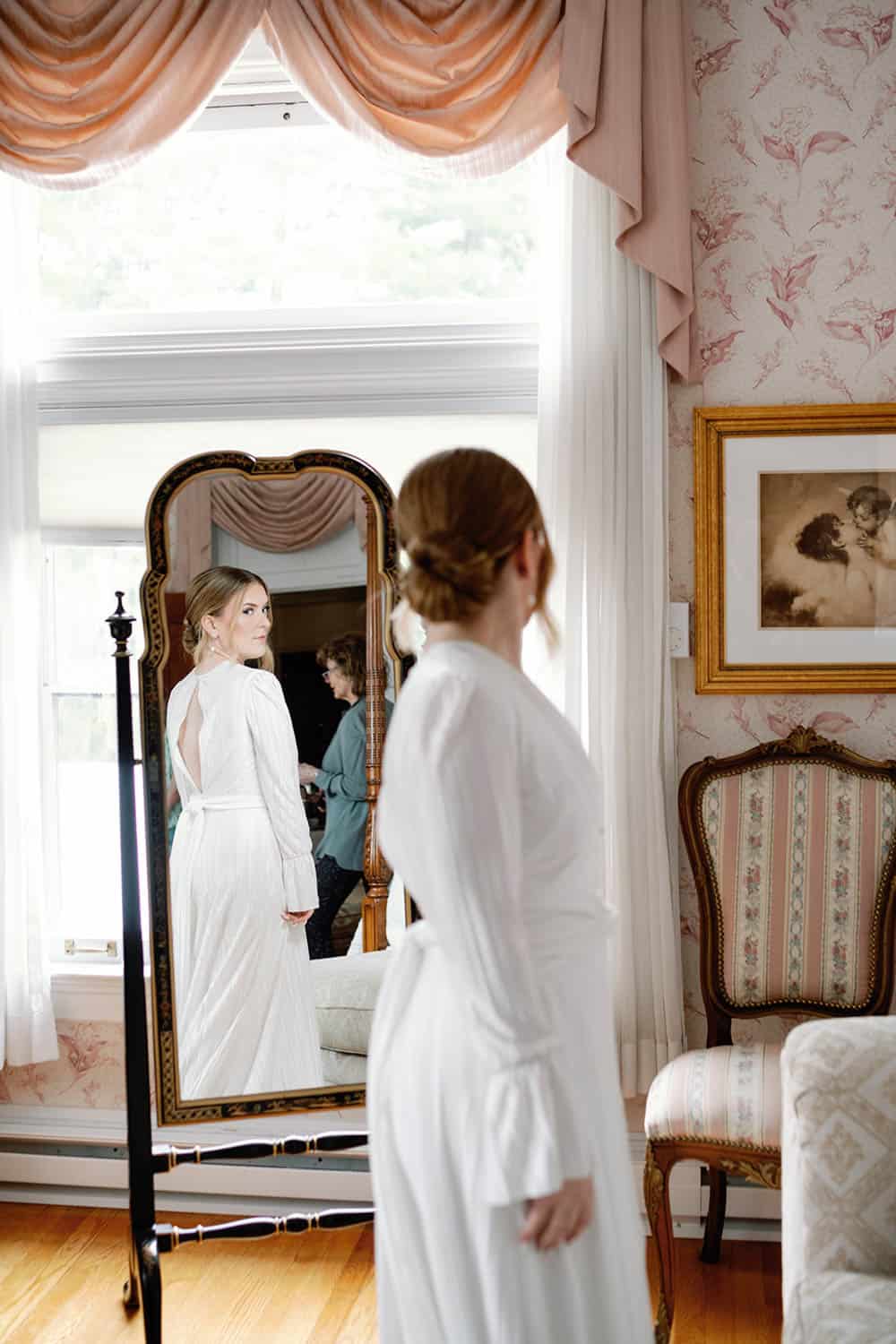 Bridal woman getting ready in a beautifully decorated room with vintage furniture and floral wallpap.