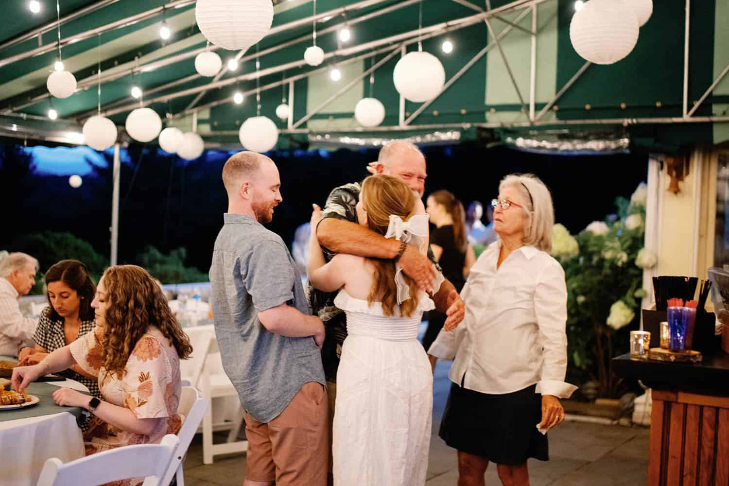 Outdoor event with guests enjoying a joyful moment under string lights.
