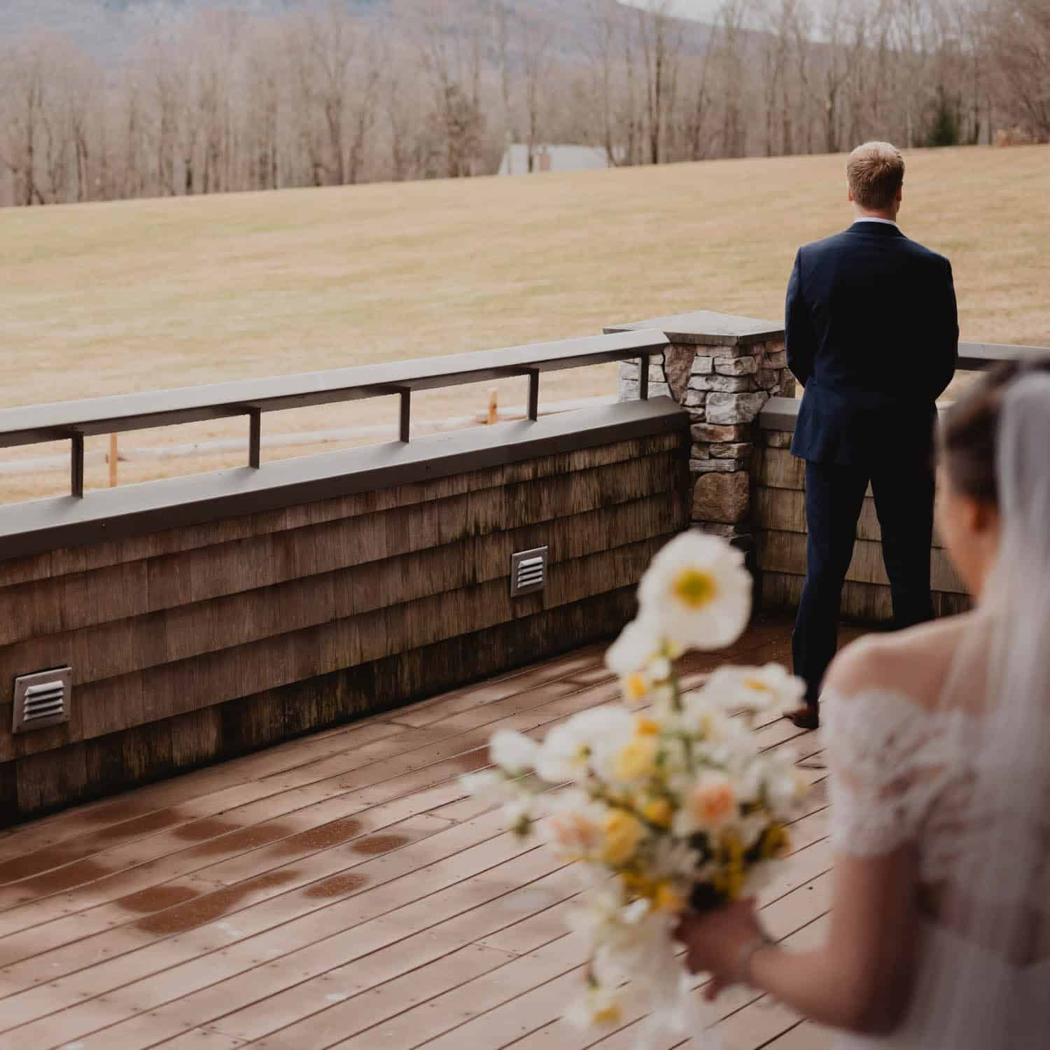 Wedding couple overlooking scenic landscape from a wooden deck.
