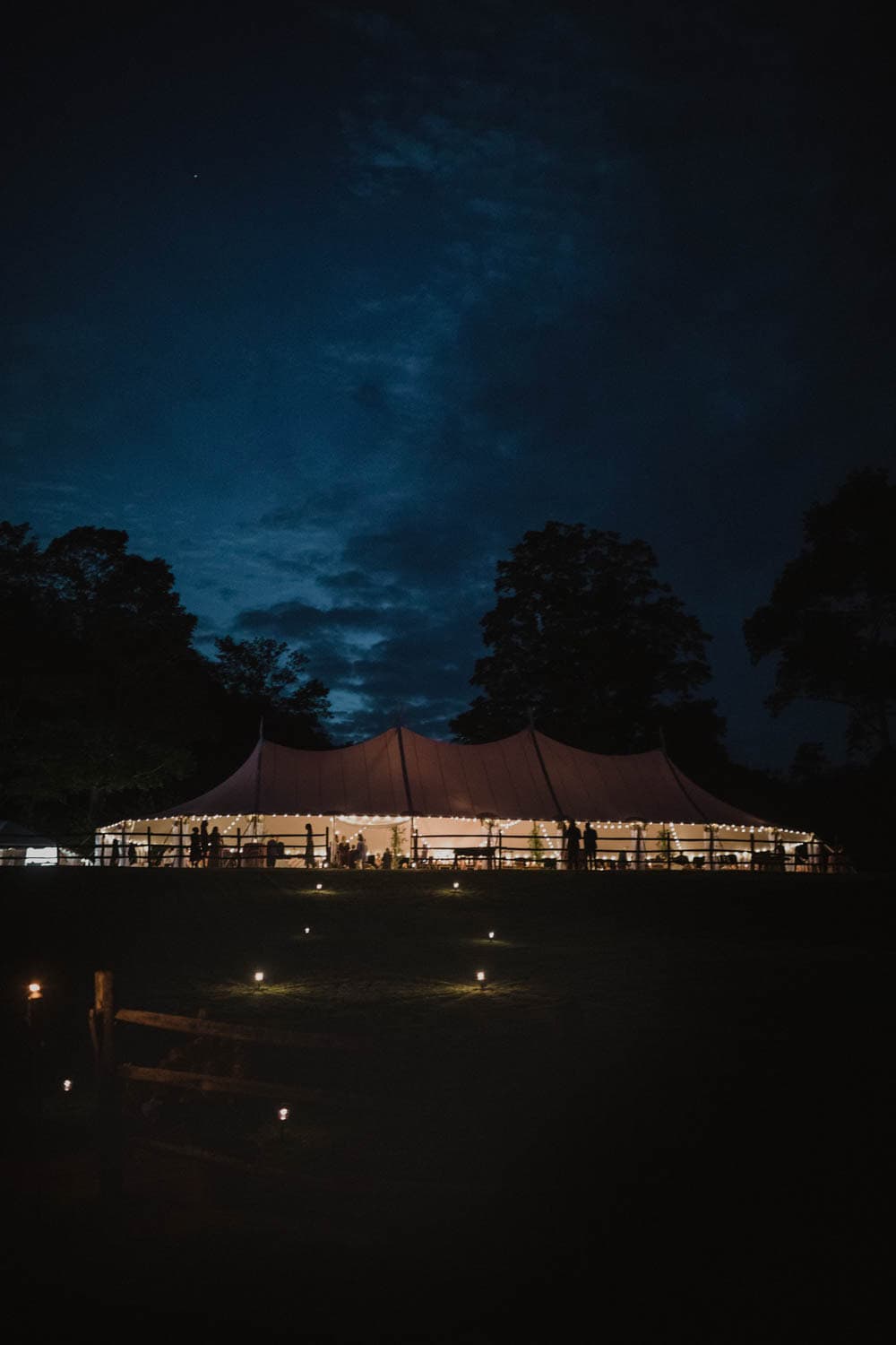 Outdoor event tent illuminated at night with a starry sky backdrop.