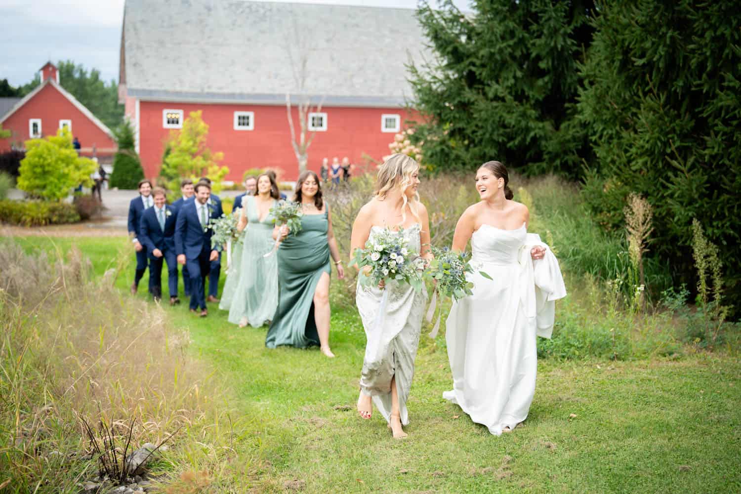 Elegant outdoor wedding procession with bridesmaids and bride in a lush green setting.
