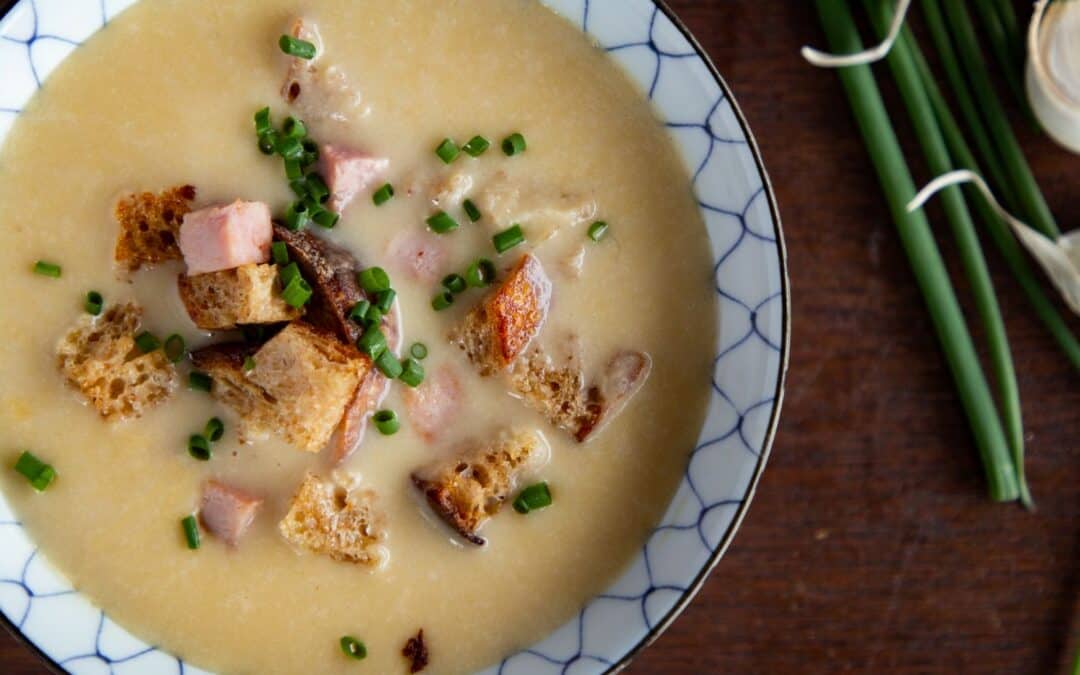 Elegant soup with croutons and ham garnished with chives, symbolizing reflection and nostalgia.
